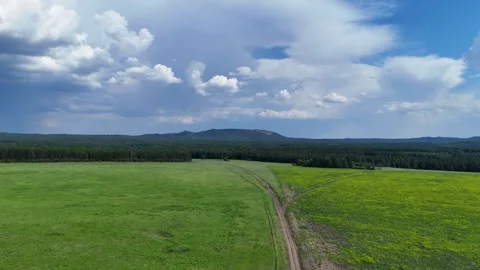 A drone takeoff from bottom to top over a picturesque green meadow with moun Stock Footage 321135270