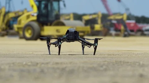 Drone takes off in front of construction equipment, exits top frame Stock Footage 80133498