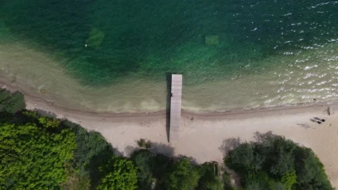 Drone takes off over pier on the turuoise water lake with sandy beach Stock Footage 155930889