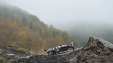 Drone takes off from rough stone in misty mountains. Fog in autumn forest Stock Footage 99003660