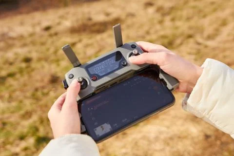 Drone is taking off by remote controller in womans hands. Concept of shooting Stock Photos