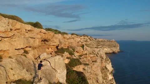 Drone taping a kid while parkouring to hear a cliff with the sea on his right Stock Footage 130957785