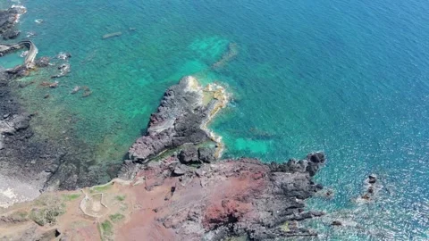 Drone tilt up focusing on a dramatic red and black volcanic cliff 4K Stock Footage 336230593
