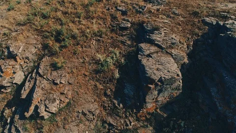 Drone tilt up shot of rocky cliffs of an island under cloudy blue sky Stock Footage 117483201