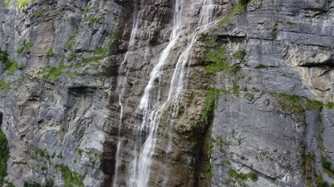 Drone Tilt of Waterfall Cascading Down Rocky Cliff in Swiss Alps Stock Footage 313562689