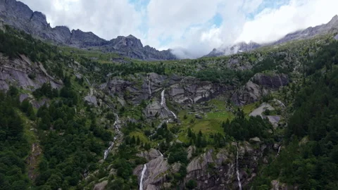 Drone tilting up and pulling away from mountain waterfall and cliffs, Swiss Alps Stock Footage 320939629