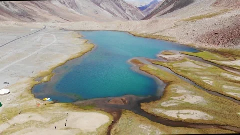 Drone tilts up from blue Chagar Tso lake to majestic Ladakh mountains Stock-Footage 336327050