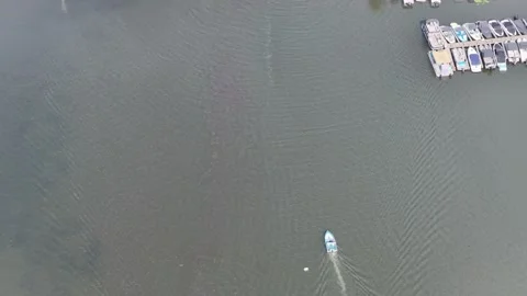 Drone tilts up from boat docks to Lake Hopatcong wooded shores Stock Footage 346882939