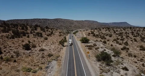 Drone tilts down over large delivery truck moving along beautiful sandstone Video stock 119958083