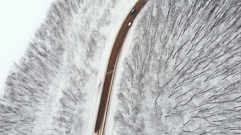 DRONE, TOP DOWN: Car drives through a slippery snow covered intersection. Flying Stock Footage 123819407