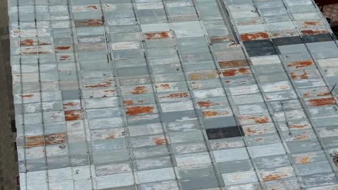 Drone top-down over corrugated metal roof with repair patches as camera tilts Stock Footage 339643822