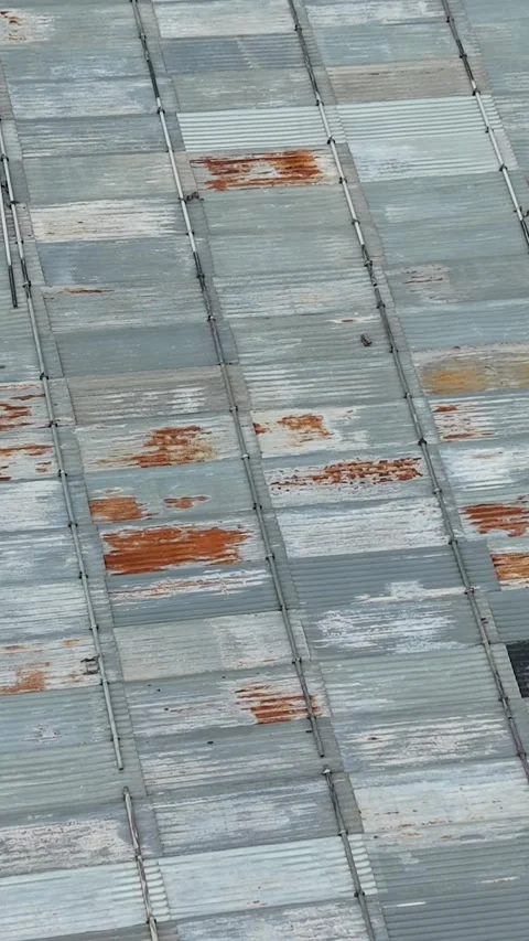 Drone top-down over corrugated metal roof with repair patches as camera tilts Stockbeeldmateriaal 339768047