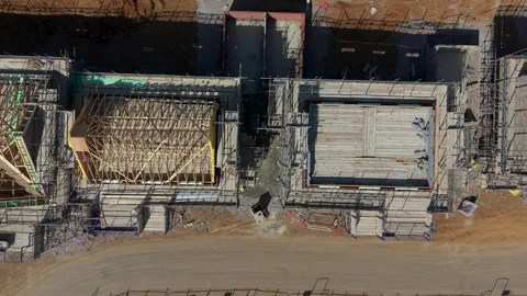 Drone top-down pan over new houses under construction with timber roof framing Stock Footage 345669395
