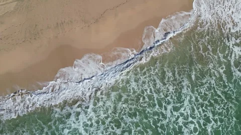 Drone top-down view of foaming waves sliding onto brown sand in Hawaii 動画素材 348263776