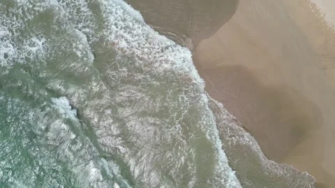 Drone top-down view of foamy waves washing onto golden sand in Hawaii Stock-Footage 347825793