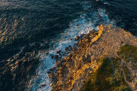 Drone top down view of ocean waves break on rocky headland, Portugal Stock Photos