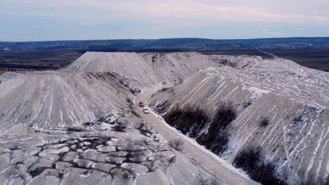 Drone top view of high hills covered with snow and serpentines. Cars drive on Stock Footage 305678957