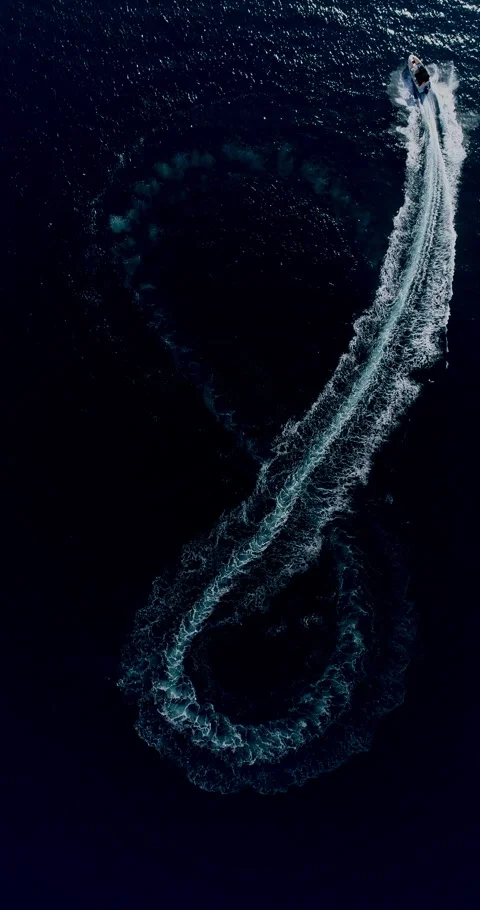 Drone top view of a motorboat creating an infinity loop on turquoise sea Stock Footage 321232695