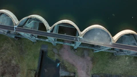 Drone top view orbit over dam with woman walking, aerial rotation shot Stock-Footage 333061355