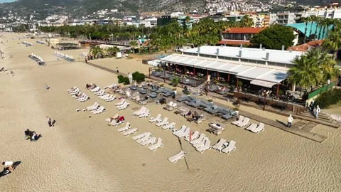 Drone top view: a sandy beach with parasol next to a restaurant terrace, shore Stock Footage 237126573