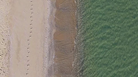 Drone top view of shoreline waves washing over sandy beach Stock Footage 321966607