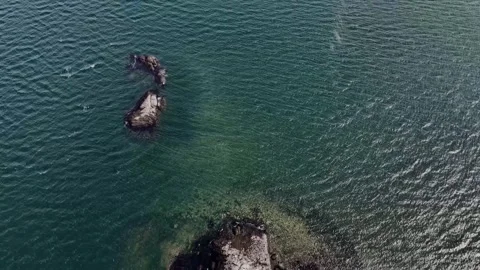 Drone top‑down shot of rocky islets in shallow turquoise waters. Video stock 345280074