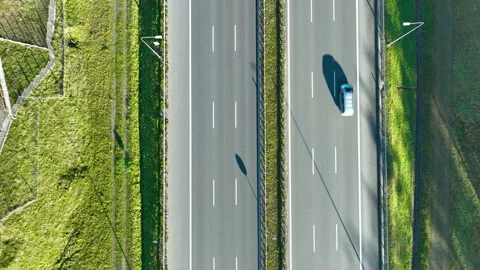 Drone top‑down view of two cars driving on parallel highway lanes with grassy Stock Footage 321863569