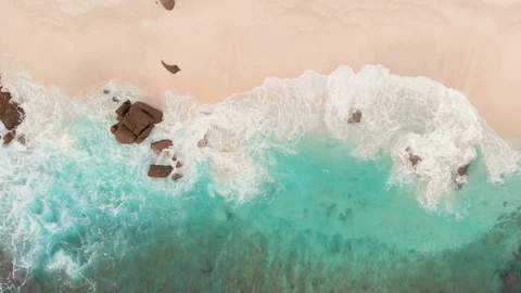 Drone topshot of waves at the beach with turquoise water on Seychelles Stock Footage