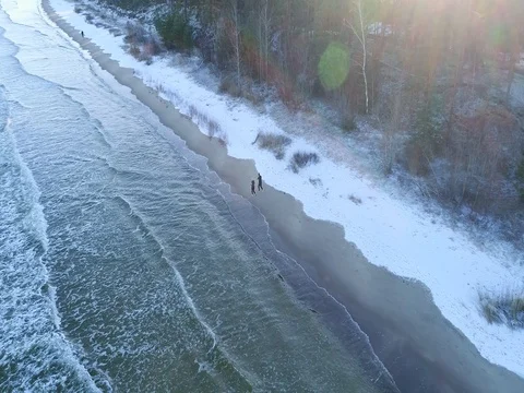 Drone tracing of a couple running along the beach in winter Stock Footage 84296906