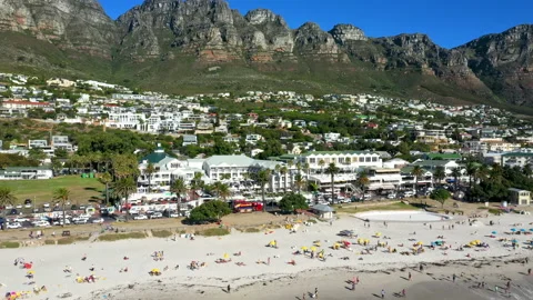 Drone tracking back to reveal a packed Camps Bay beach with its blue water Stock Footage 170726563