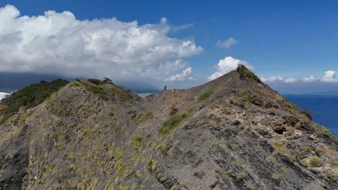Drone tracking hiker along Hon My Giang ridge with shipyard backdrop 動画素材 337344882