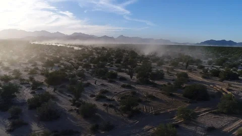 Drone tracking left to right wide shot dust trails from vehicles in open desert Stock Footage 104883948