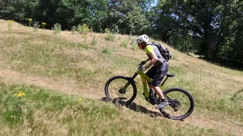 Drone tracking mountain biker uphill on Ebike grassy hill climb Stock Footage 344907924