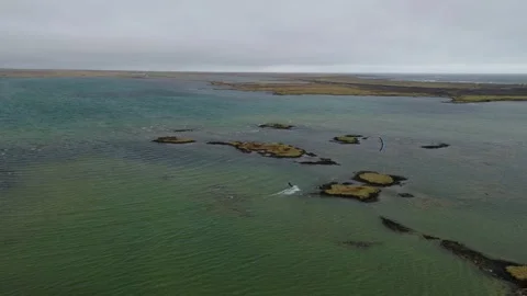 Drone tracking orbit around paraglider above Herdísarvik lagoon and volcanic 스톡 동영상 344125280