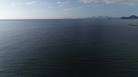 Drone Tracking Over Ocean with View of Mainland and Long Jetty Stock Footage 100308655