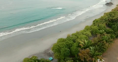 Drone tracking pullback above couple walking along tropical Pacific beach in Vídeo Stock 340543710
