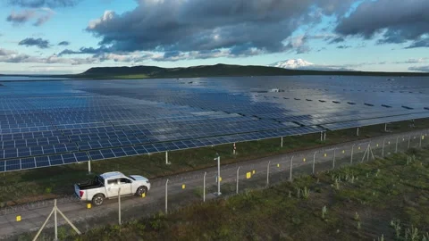 Drone tracking shot along solar panel rows near fenced area Stock Footage 324543747