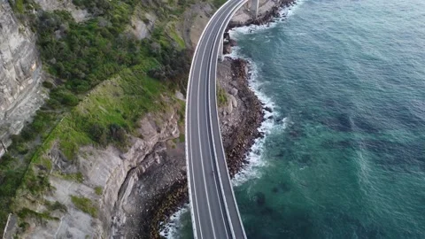 Drone tracking shot of a cycle on a sea cliff bridge Stock Footage 143620110
