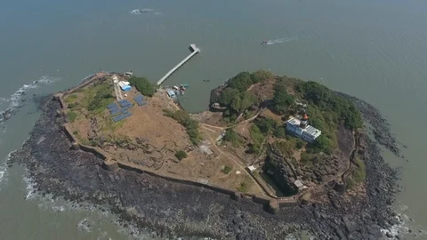 Drone tracking shot of an island with a lighthouse on a rocky beach Stock Footage 117357140