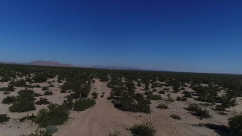 Drone tracking shot of motorcycle racing across desert landscape Stock Footage 104883873