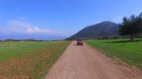 Drone tracking shot as a small buggy car races down a dirt path towards 動画素材 95666052