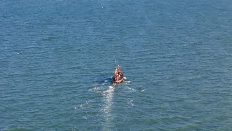 Drone tracking shot of a small red fishing boat crossing turquoise sea water Vidéo 311039727