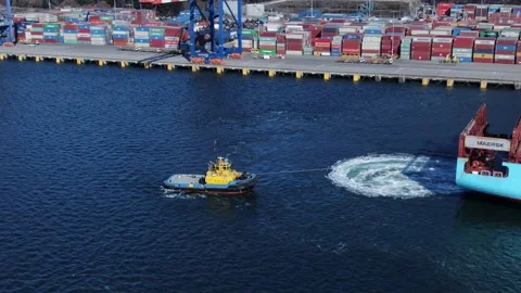 Drone tracking shot of tug boat assisting container ship in leaving its berth Stock Footage 149209697