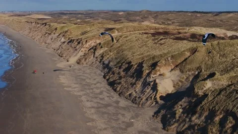 Drone tracking shot of two paragliders soaring over Castricum beach and Video stock 263518791