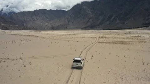 Drone tracking shot of a white car driving on desert race track in the mountains Stock Footage 131713859