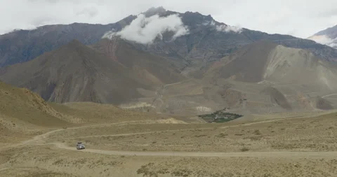 Drone tracking SUV driving through rugged terrain in scenic Mustang region Nepal Stockbeeldmateriaal 335152432