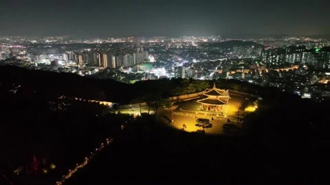 Drone tracking view of pavilion on hilltop with city skyline at night Stock Footage 313641134
