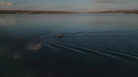 Drone tracking a wakeboard boat carving across Lake Paranoa at sunset near Stock Footage 342643131