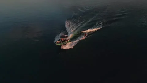 Drone tracking a wakeboarder and boat carving across Lake Paranoa during sunset Stock Footage 342580067