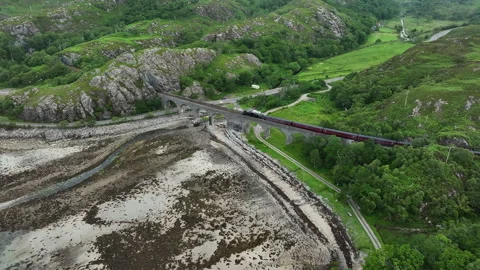 Drone tracks Jacobite steam train crossing Lochailort viaduct Stock Footage 330591622
